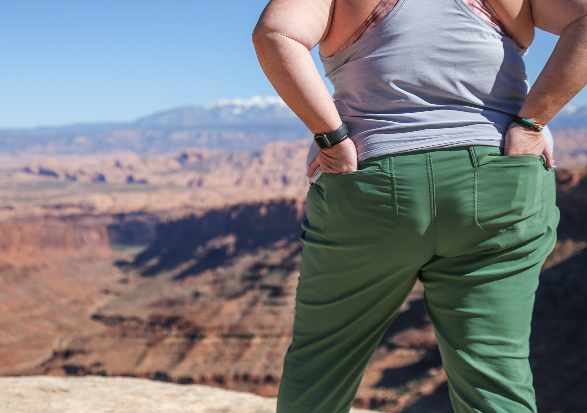 A plus size woman standing in green plus size hiking pants overlooking the desert. 